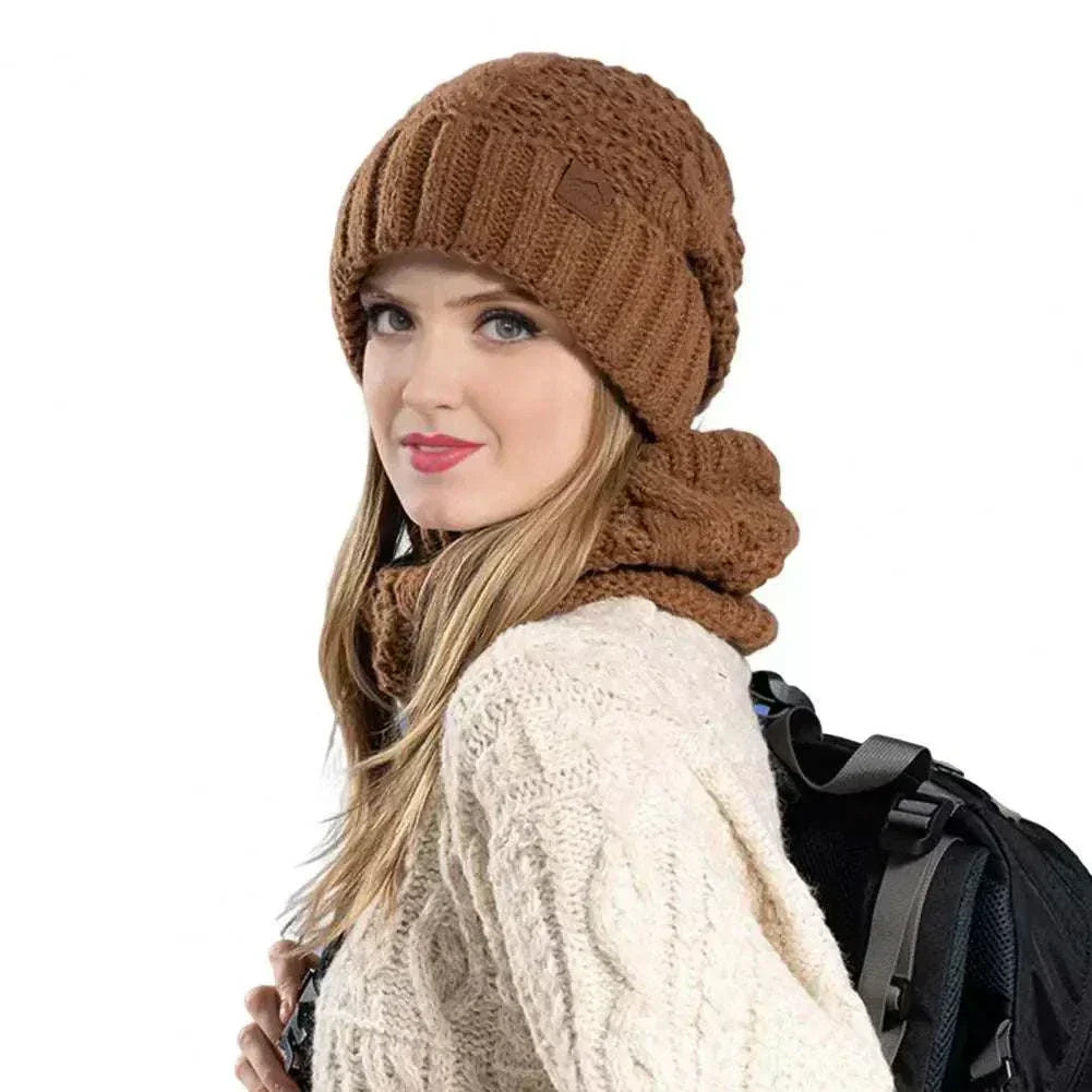 Woman wearing Glorious Winter Glow Duo brown knit hat and scarf set with cream sweater and backpack