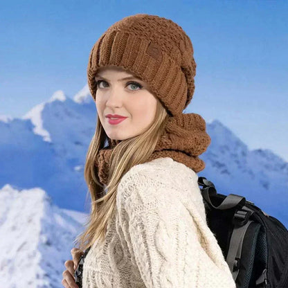 Woman wearing Glorious™ Winter Glow Duo brown knit hat and scarf set in snowy mountain background
